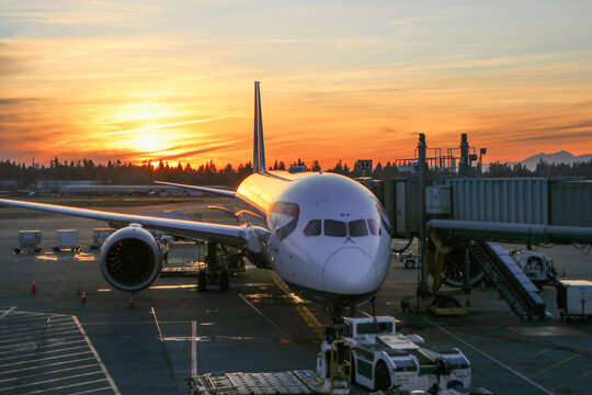 A British Airways Boeing 787 parked at a gate with the sun setting in the background at Seattle-Tacoma International Airport - Seattle, Washington, USA
