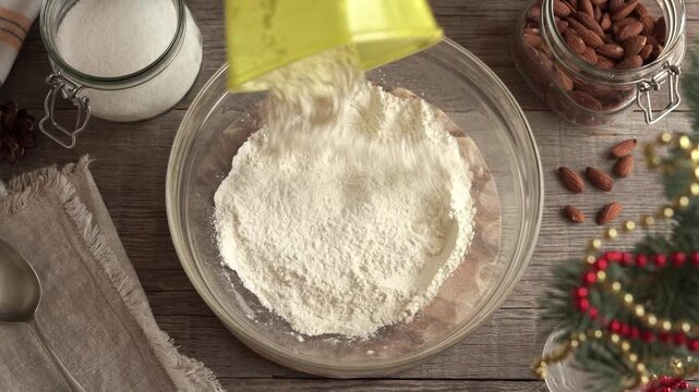 Adding wheat flour into a bowl with wheat and almonds in the background - baking vanilla crescent Christmas cookies called Kipferl