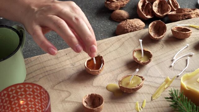 Homemade preparation of Christmas candles from nut shells and beeswax - inserting the wick