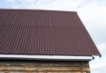Fototapeta premium modern construction of the roof with red metal siding to a wooden house in the garden
