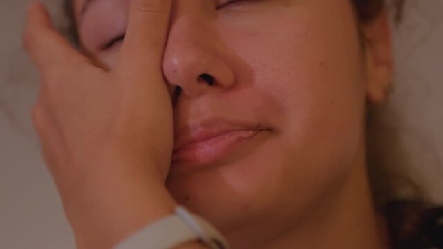 Closeup woman face showing anxious exhaustion, tight frames capture chin, mouth, hand covering eye, subtle breathing, warm low light, introspective mood, candid skincare detail, quiet stillness