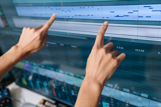 Sound engineer hands interacting with digital audio workstation software, creating and editing music production with modern midi notes on computer screen, close-up
