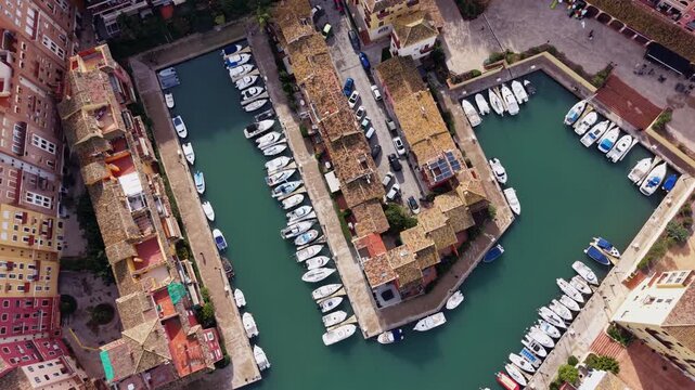 Vertical aerial shot looking straight down at Port Saplaya in Alboraya, Valencia, Spain, highlighting turquoise marina canals, docked boats, and compact coastal housing in a clean pattern