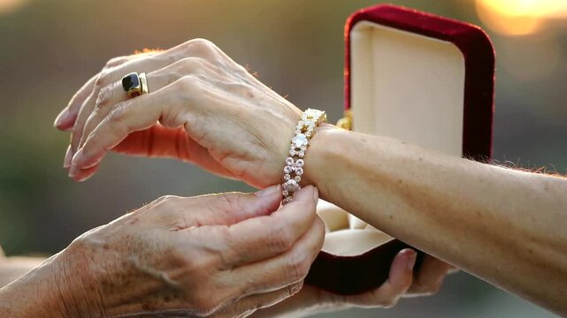 Elderly hands fastening luxury gemstone bracelet gift in jewelry box