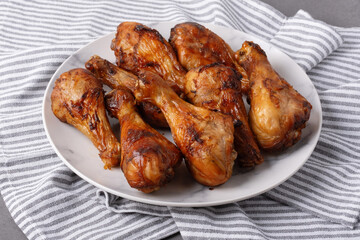 Grilled chicken drumsticks on a plate with a striped cloth underneath at a casual dinner table