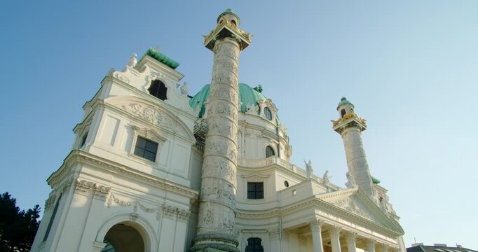Cinematic shot of historical Karlskirche Church in Vienna, Austria, EU. Baroque landmark with green dome and twin columns under a clear summer sky. Travel and tourism. 4K low angle orbit video