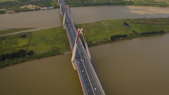 Aerial footage of vehicles driving on the modern nhat tan cable-stayed bridge over the red river