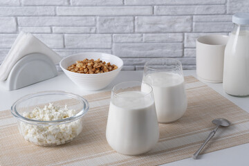 Kefir, buttermilk or yogurt, cottage cheese with granola. Yogurt in glass on white wooden background. Probiotic cold fermented dairy drink. Gut health, fermented products, healthy gut flora concept