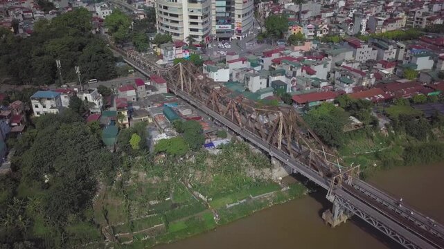 Aerial drone shot flying over the historic long bien bridge and the red river in hanoi, vietnam