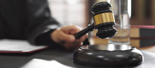 Judge striking gavel at desk indoors, closeup