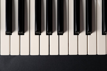 Naklejka premium Piano keys on black background, top view. Musical instrument