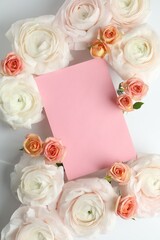 Naklejka premium Beautiful ranunculuses, roses and blank card on white background, flat lay. Mockup for design