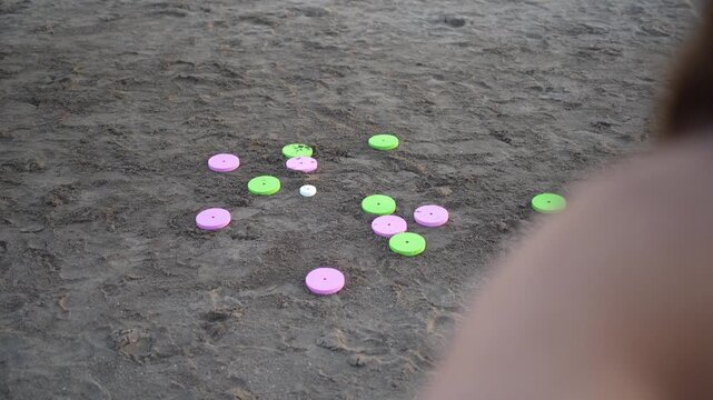 Woman playing a game of tejo on a sandy beach