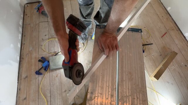 Cutting a plastic corner piece with a multi-tool. A man's hands hold a multi-tool circular saw. Close-up of the cutting object, viewed from above. Cutting materials at a construction site. Home improv