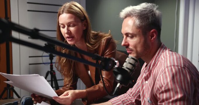 Podcast host and producer review and analyze printed charts, discuss platform analytics, key topics, and audience growth trends while preparing for informative podcast episode before recording session