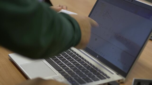 Teacher Helping Student Solve Math Problem Using Laptop and Smart Calculator in Classroom