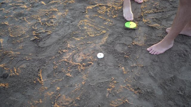 People picking up tejo game pieces from the sand on the beach