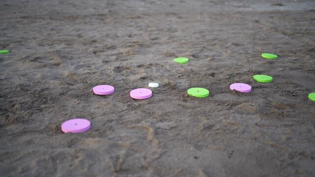 Colorful tejo game pieces landing on the beach sand