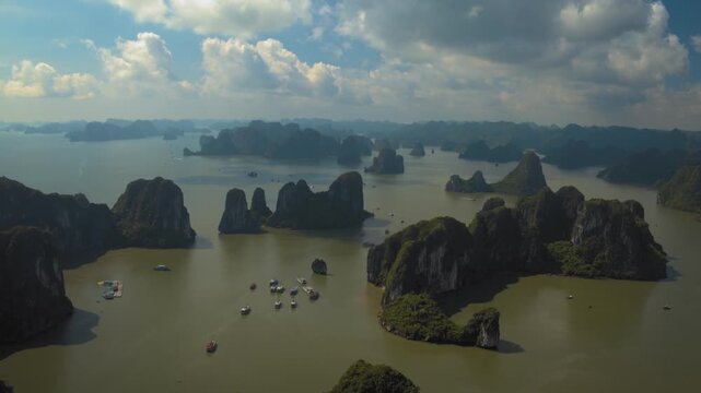 Majestic aerial footage flying over tourist boats sailing among the limestone karsts of halong bay