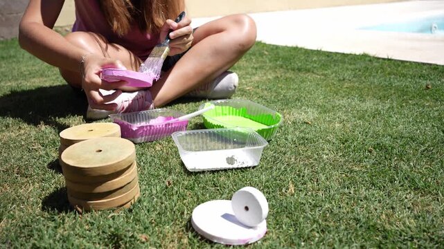 Unrecognizable woman painting tejo discs outdoors