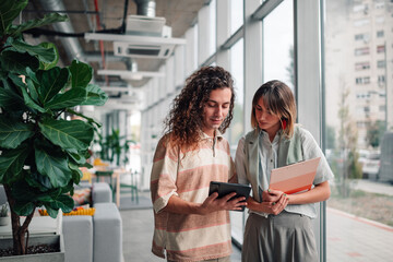 Coworkers collaborating on tablet in modern office