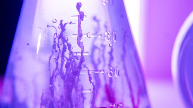 Close-up macro chemical reaction in laboratory glassware with colorful liquid in neon light. Science experiment, chemical research, medical laboratory, background, test tube, numbers