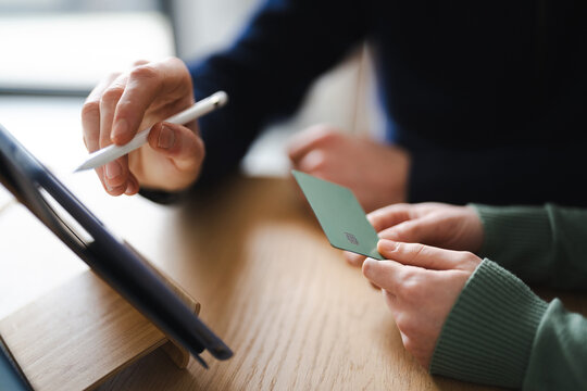 Two people are using a tablet and a payment card for online shopping or a transaction.