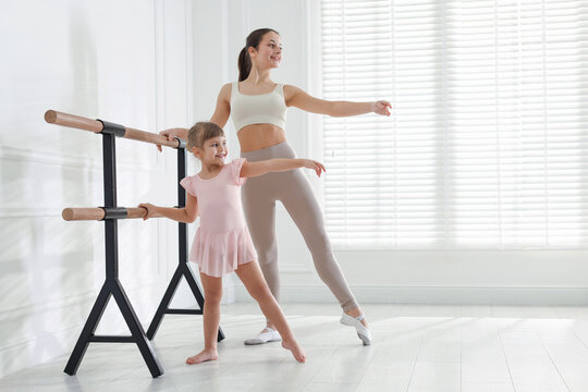 Ballet teacher training cute little girl near barre in dance studio. Space for text