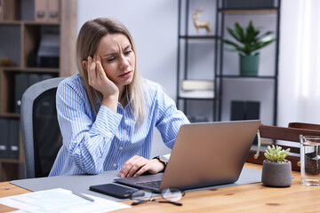 Fototapeta premium Woman feeling fatigue at wooden desk in office