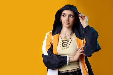 Beautiful young woman with piercings in windbreaker on yellow background. Space for text © New Africa