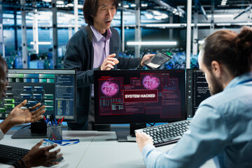 Manager supervising server farm admins alerted by hack warning, securing systems from cyberattack accessing confidential data. Teamworking data center colleagues defending rigs during security breach © DC Studio