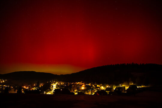 Village lights under red aurora borealis