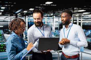 Multiethnic employees team collaborating on maintenance for server rigs and handling AI processing...