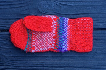 one red winter woolen mitten with a pattern lies on a black table