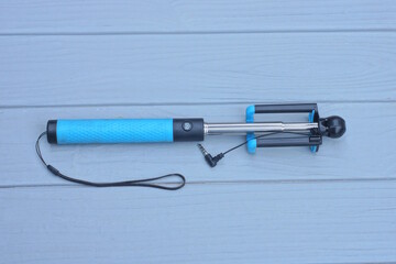 one black blue selfie stick lies on a gray wooden table