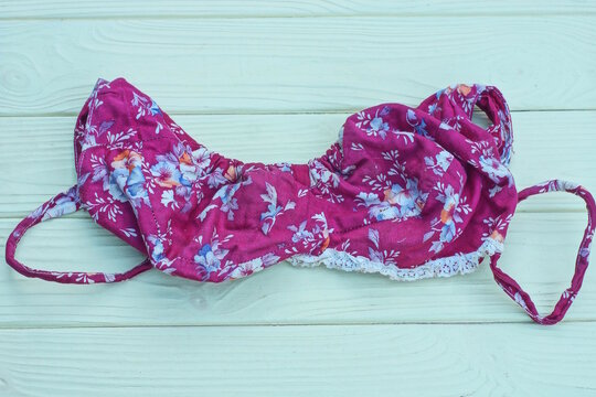 one red bra with a colorful pattern lies on a yellow wooden table
