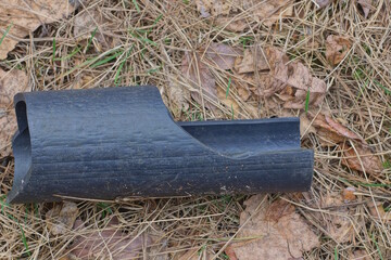 one piece of old dirty black plastic pipe lies on the ground on a summer street