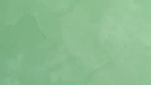 Subtle green textured wall background with abstract plaster details