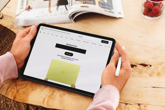 Person holding tablet pre-ordering macbook neo online