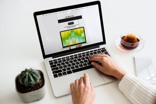 Person typing on laptop browsing macbook neo