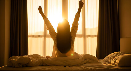 Woman stretching on bed with arms up at sunrise in hotel room