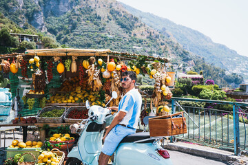 Traveler on vintage scooter stopping at colorful fruit stand in Positano Italy © Angel