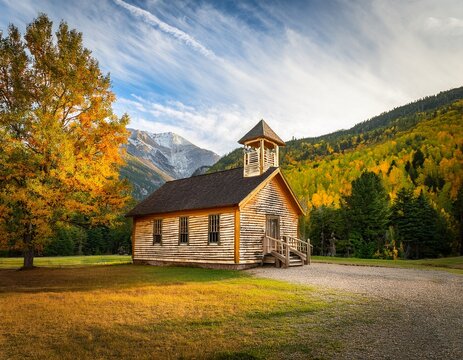 vintage single room schoolhouse surrounded by woods and mountains in early fall serving as a historical education site