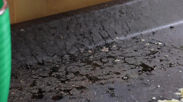 Greasy kitchen griddle surface with oil splatters and food residue, textured cooking background reflecting busy restaurant workflow and intense culinary preparation