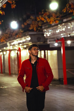 Young man in red jacket in illuminated street in Japan at night