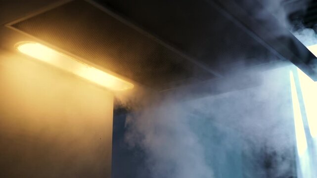Kitchen extractor hood removing steam from stove, close view of ventilation system in action during meal preparation at home