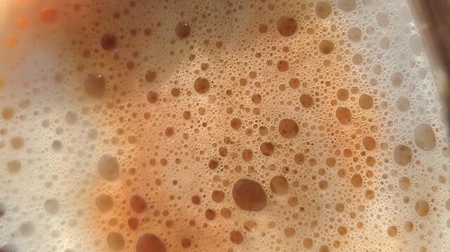 
Extreme close-up of brown tea bubbles and foam on the surface.