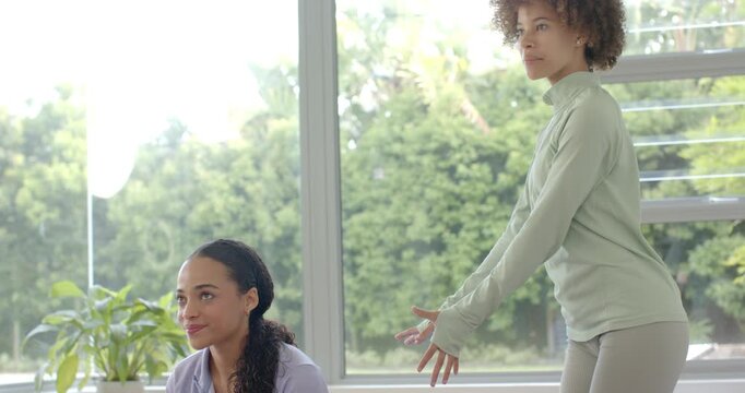 African American instructor gesturing and cueing student into prone backbend on purple mat for form
