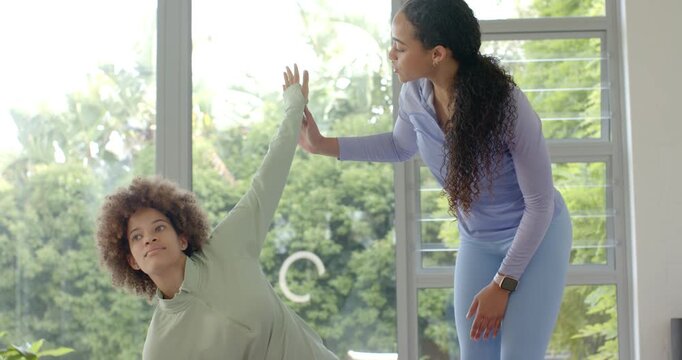 African-American female coach  and  client seeing reach guiding stretch at home aligning arm smartwa