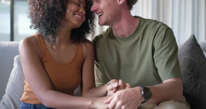 Couple sitting on sofa man taking her hand, sliding ring onto her finger sharing affection